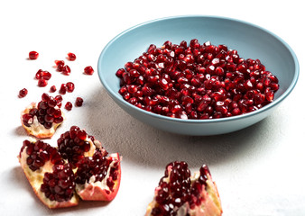 Grains of tasty, bright red peeled pomegranate lie in a plate on a white background. Close-up.