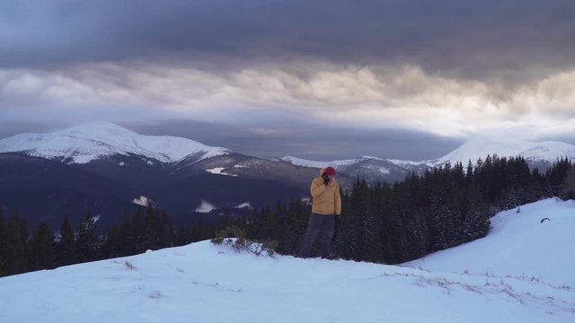 A traveler talks on the phone in the mountains in winter. He screams, gets angry and throws the phone into the snow. Carpathian mountain range. 4K