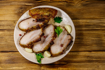 Baked pork belly in a plate on wooden table. Top view