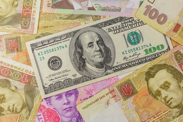 Fototapeta na wymiar One hundred dollar bill on a background of different ukrainian hryvnia banknotes