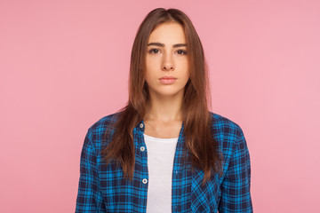 Portrait of serious unsmiling girl in checkered shirt looking at camera with calm attentive focused...
