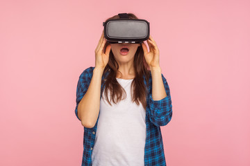Portrait of amazed gamer girl in checkered shirt wearing vr headset, playing virtual reality game with shocked facial expression, surprised by innovative technology. indoor studio shot, isolated
