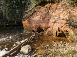 sunny landscape with sandstone cliff on river bank, fast flowing river water