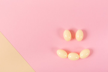 Composition of pills and capsules on a pink background in the form of a smile. Happy emotions. Psychological help.