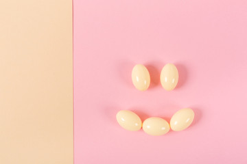 Composition of pills and capsules on a pink background in the form of a smile. Happy emotions. Psychological help.