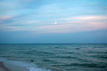 full moon in sunset evening sky over the ocean