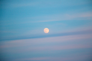 full moon in evening sky with clouds