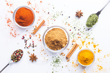 Variety of spices and herbs in spoons and bowls on white background. Top view. Cooking ingredients...
