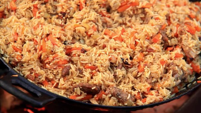 Traditional Middle Eastern rice dish pilaf cooking on open fire. Culinary background footage. Healthy eating concept.