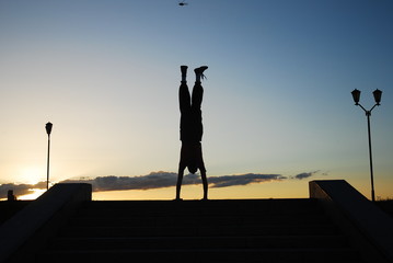 alone kung fu warrior fulfills a handstand against the sunset sky