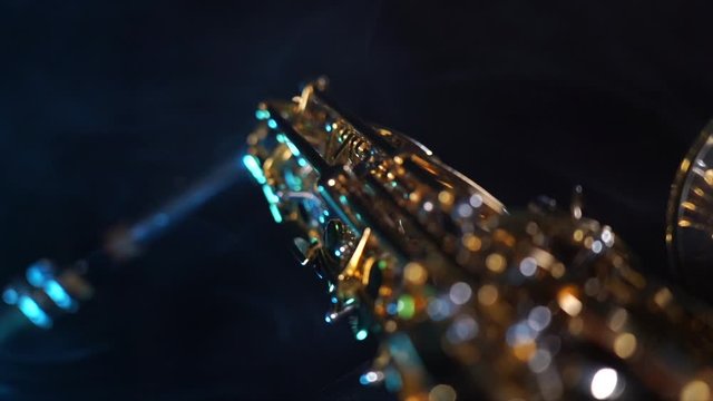 Golden shiny alto saxophone on black background with blue smoke