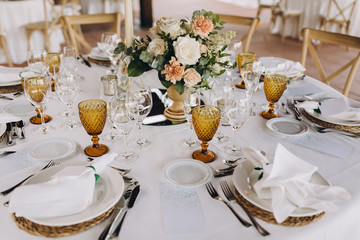 banquet tables are decorated with compositions of flowers and greenery, on the tables are plates...