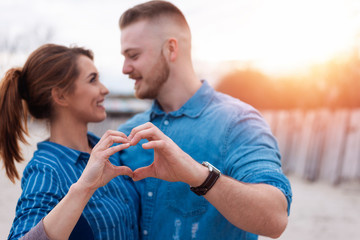 Young couple in love making heart with hands