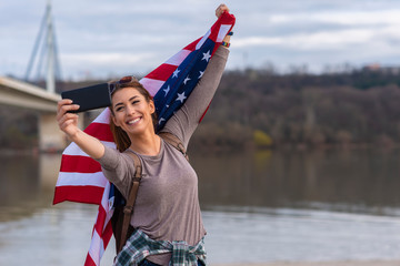 Young beautiful woman with american flag doing selfie