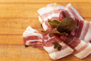 On a wooden Board is meat, cut into small pieces, and spices: Bay leaf, black pepper peas