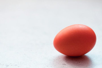 Red easter egg on grey concrete table. Front view. Selective focus. Easter decoration. 