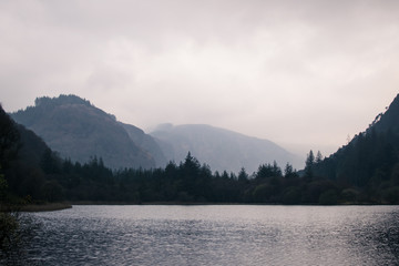 Lago en Irlanda en un día nublado con bosques y montañas a lo lejos