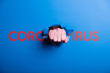 Human hand breaking a blue paper, in the hand is a syringe with the medicine against the...