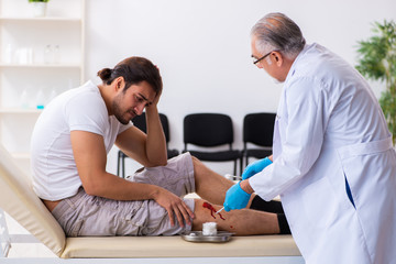 Fototapeta na wymiar Leg injured man visiting old doctor in first aid concept