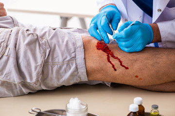 Leg injured man visiting old doctor in first aid concept