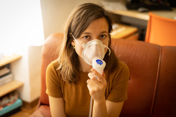 handsome girl brunette with Coronavirus wears protective mask and reads his temperature on a...