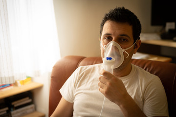 COVID-19 Pandemic Coronavirus; Close-up of young man using respirator machine for breathing at home. man using CPAP machine and wearing nasal mask