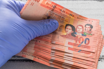 Bolivian money, 100 bolivianos kept in rubber gloves.  The concept of economy and financial threats during the Coronavirus pandemic