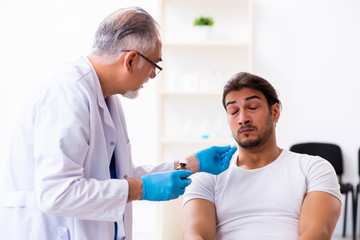 Obraz premium Leg injured man visiting old doctor in first aid concept