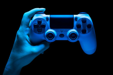 Hyman hand holding white video game gamepad in neon lights isolated on a black