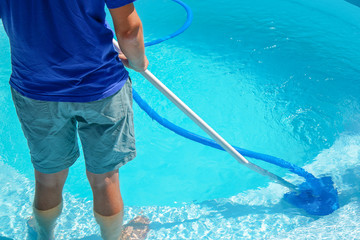 swimming pool cleaning. a man is cleaning the pool. service care