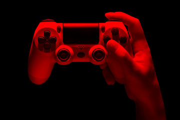 Hyman hand holding white video game gamepad in neon lights isolated on a black