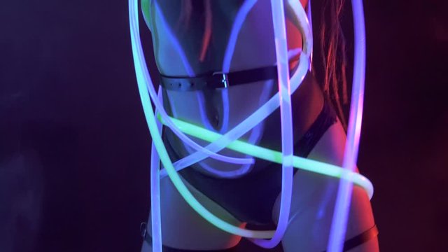 Portrait of a Girl with Dreadlocks in Neon UF Light. Model Girl dancing with glowing tubes with Psychedelic MakeUp, Art Design of Female Disco Dancer Model in UV, Colorful Abstract Make-Up.