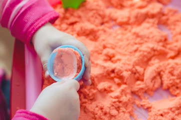 The hands of a child playing with kinetic sand