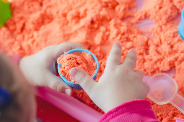 The hands of a child playing with kinetic sand