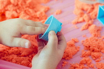 The hands of a child playing with kinetic sand