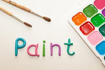 MULTI-COLORED PALETTE AND BRUSHES, PAINT ON A WHITE BACKGROUND