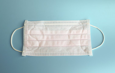 Light pink  medical  face Mask isolated on light blue blackground  for protection against  protection coronavirus COVID-19 prevention of the spread of virus and pandemic .