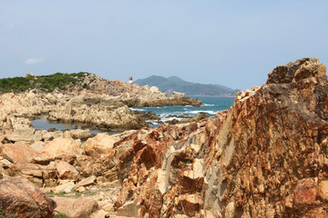 Fototapeta na wymiar Rock beach with lighthouse in Vietnam