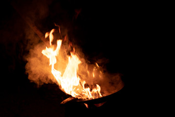 Red orange flame from the fire on the pan roasting cashews..fire,heat energy that ignites fuel at night.black background. select focus.