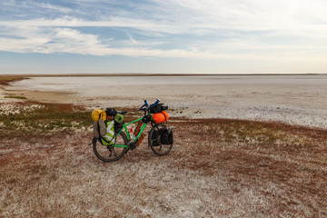 Fototapeta premium tourist bicycle with bags stands on the shore of a dry salt lake in the steppe of Kazakhstan
