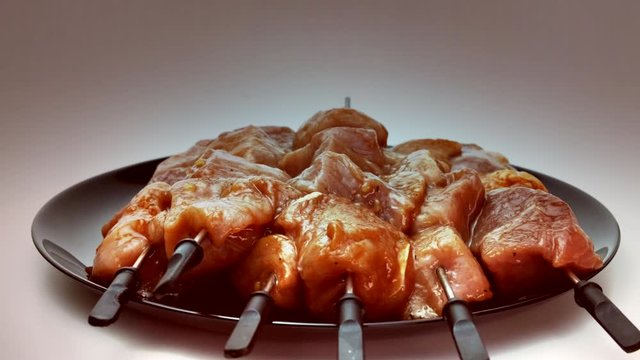 Chopped meat for barbecue is strung on metal skewers and ready for frying. skewered meat On a black plate. 360 rotation.
