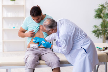 Injured young man visiting experienced male doctor