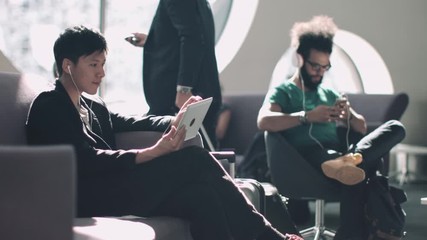 Asian Male watching digital tablet in airport waiting lounge