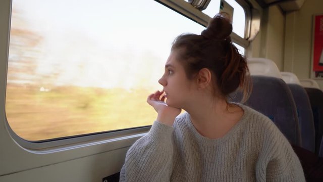 Beautiful, young lady travels by train, looks out the window  and  resent looking out the window