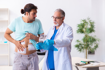 Injured young man visiting experienced male doctor