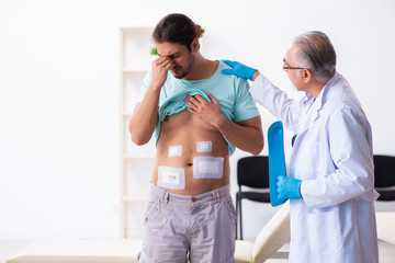 Obraz premium Injured young man visiting experienced male doctor