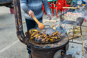 Potatoes are fried on a huge table. A man stirs a potato with a wooden spoon. Big stove. Carnival celebration. Bilogorodka. Ukraine. Spring meeting, February 25, 2017