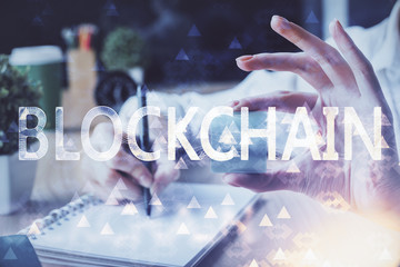 Cryptocurrency hologram over hands taking notes background. Concept of blockchain. Multi exposure