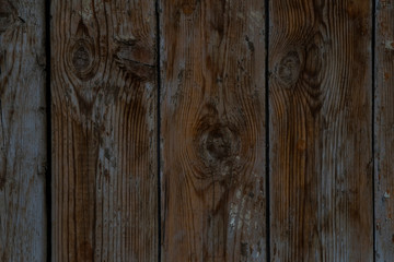 Wooden boards. Grunge texture of wooden boards. Abstract wooden background. The rough texture of the raw wood. Old fence made of wooden boards. Deep cracks. Remains of old paint on the boards