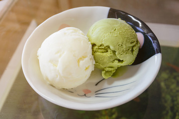 Green tea matcha ice cream scoop in white bowl from top-view isolated on white background....